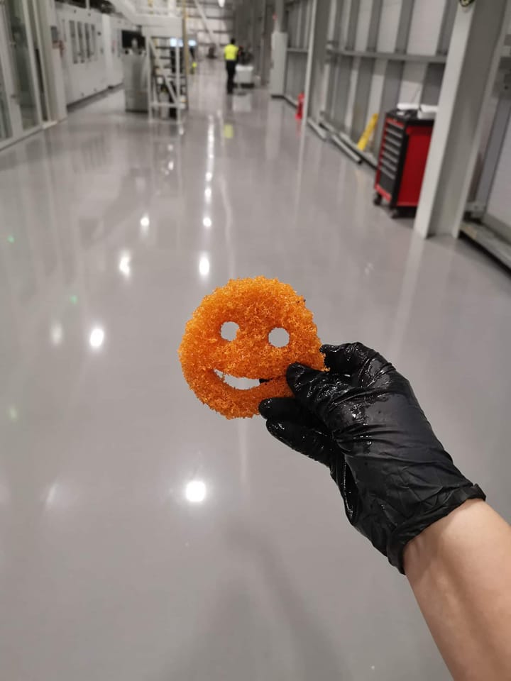 sponge someone wearing a black rubber glove holding an orange smiley face sponge